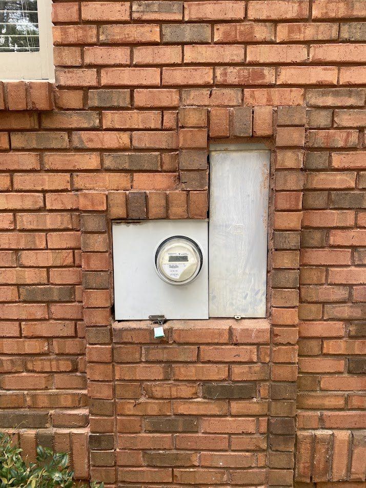 Old 200-amp meter and panel recessed in a brick wall