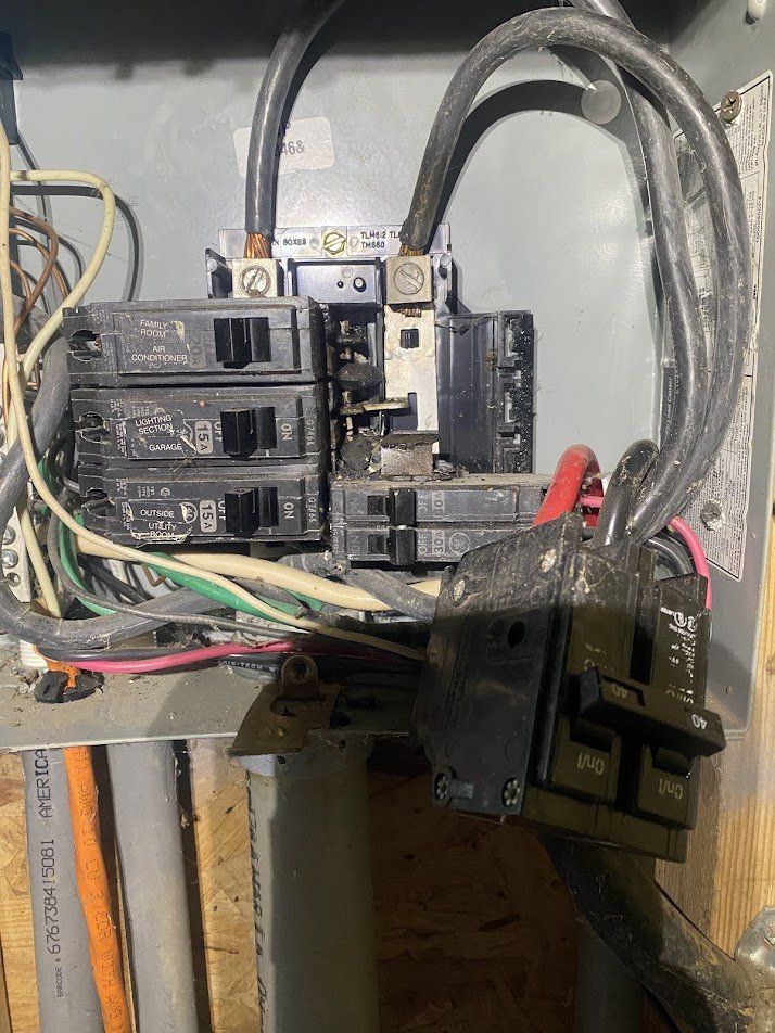 Old subpanel with a damaged breaker pulled out, showing heat damage