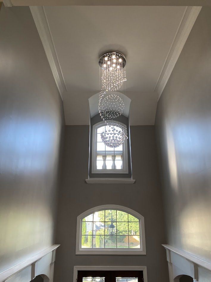 Tall crystal sphere chandelier hanging in a two-story foyer