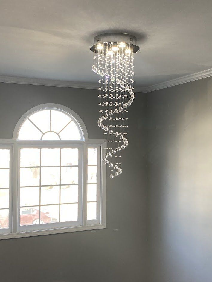 Spiral crystal chandelier installed beside an arched window