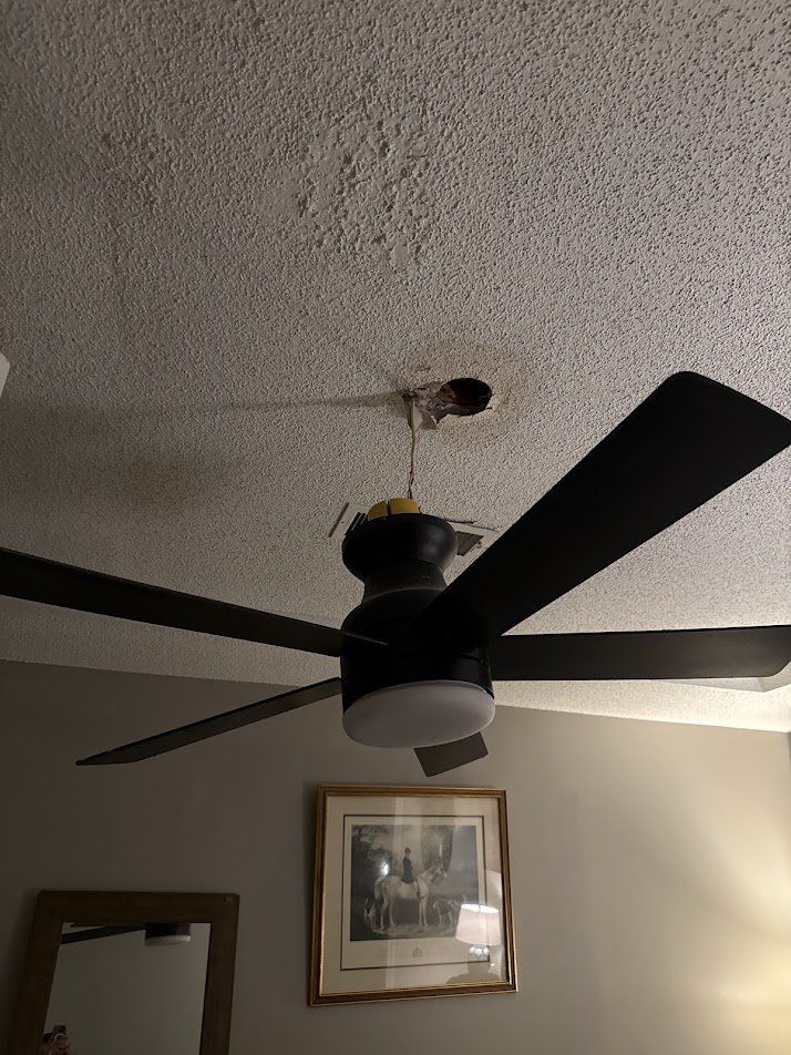 Ceiling fan hanging loose from a scorched, damaged ceiling box