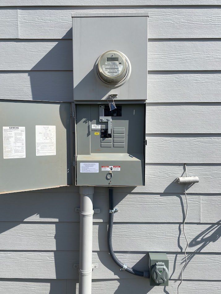 Meter main with generator breaker and a portable generator inlet mounted below on the siding